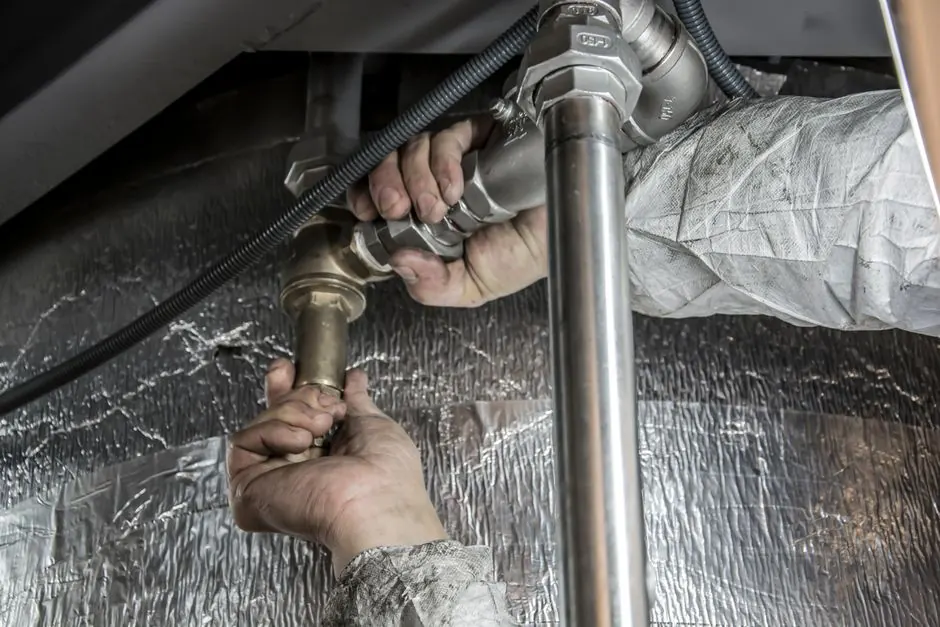Plumber tightening a fitting on a leaking supply pipe